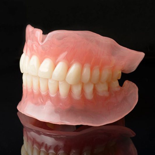 Set of full dentures isolated against dark background