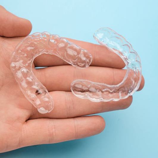 Two Invisalign aligners resting on person’s hand